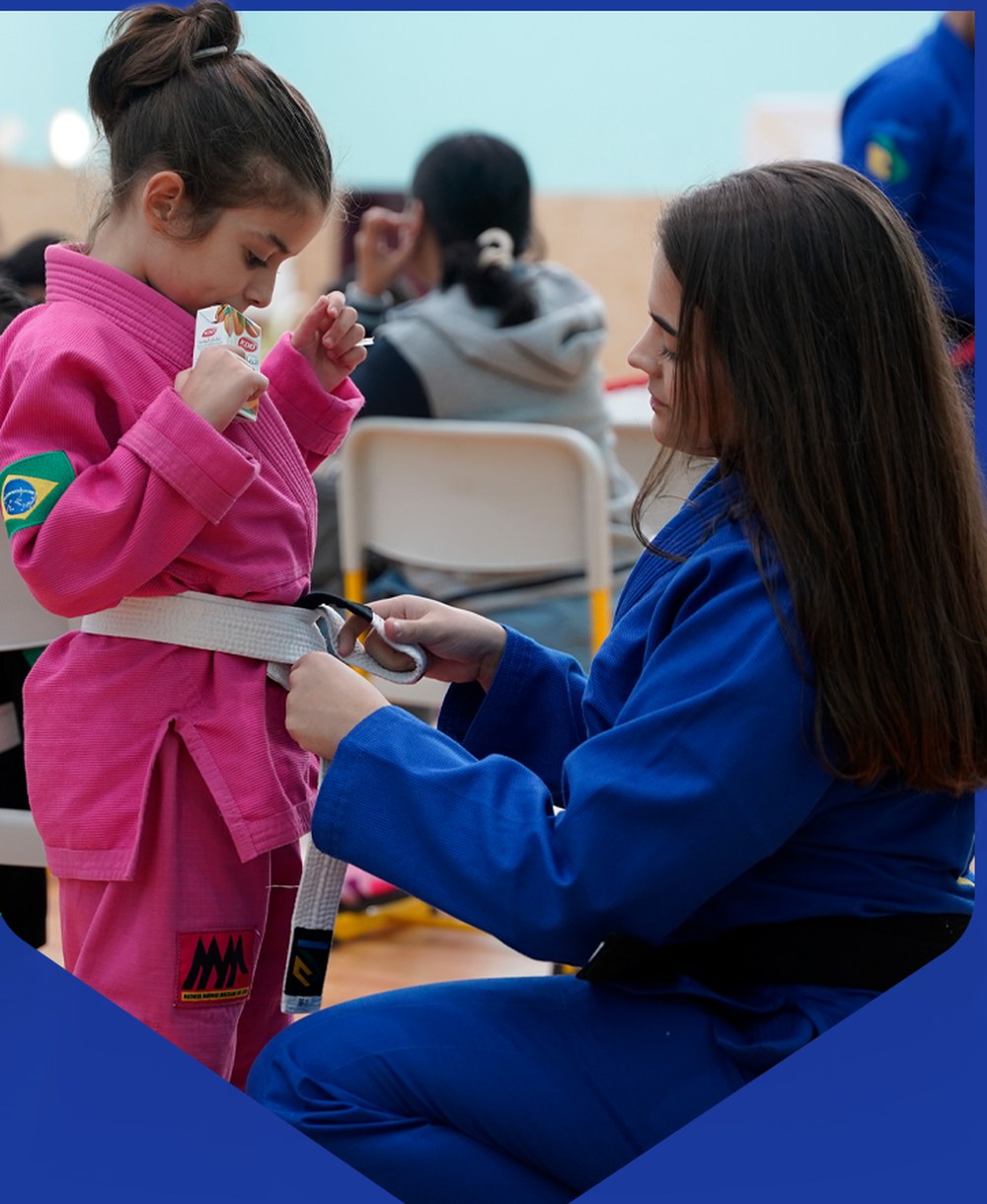 Coach tying a young student's white belt before class