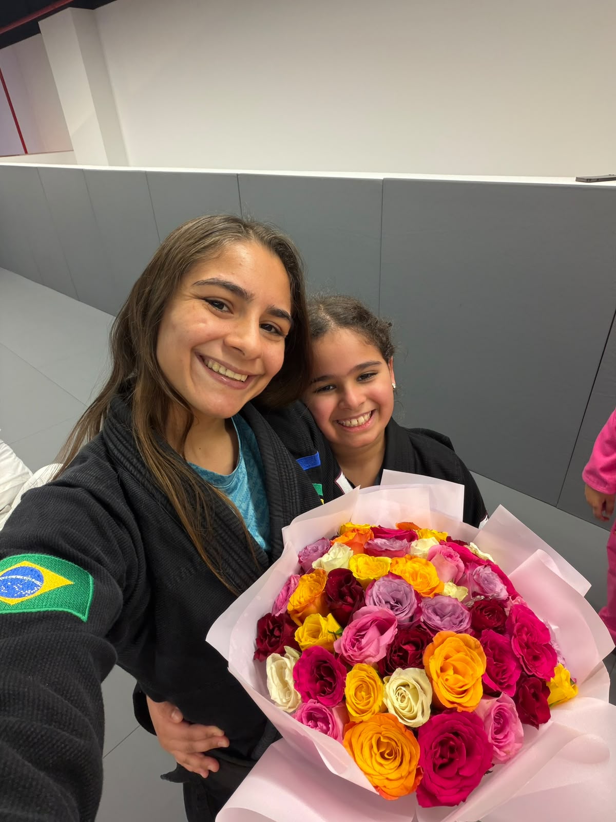 Female Brazilian Jiu Jitsu coach and her young student holding flowers at the academy in Doha